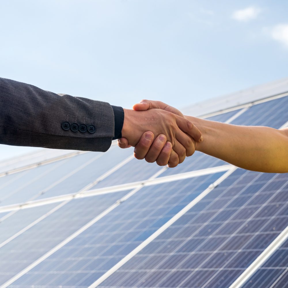 Duas pessoas se cumprimentando com a placa solar no fundo